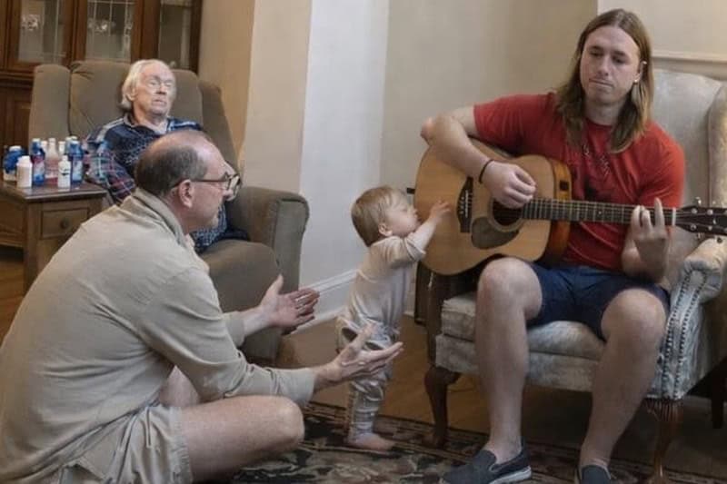 family-hospice-room young man plays guitar with family members in hospice room